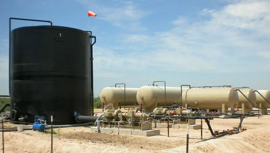 A large black tank sitting next to a gas line.