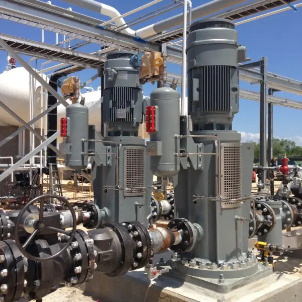 Industrial pumps and pipes under blue sky.